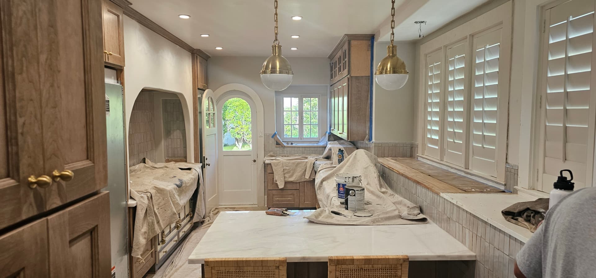 Kitchen masked and drop-clothed mid-project during cabinet and trim painting