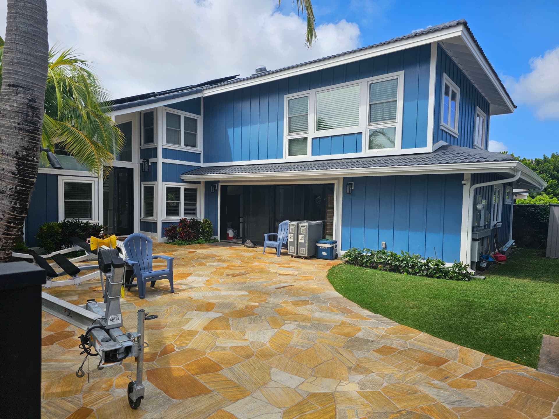 Two-story home painted deep blue with crisp white trim beside a flagstone patio