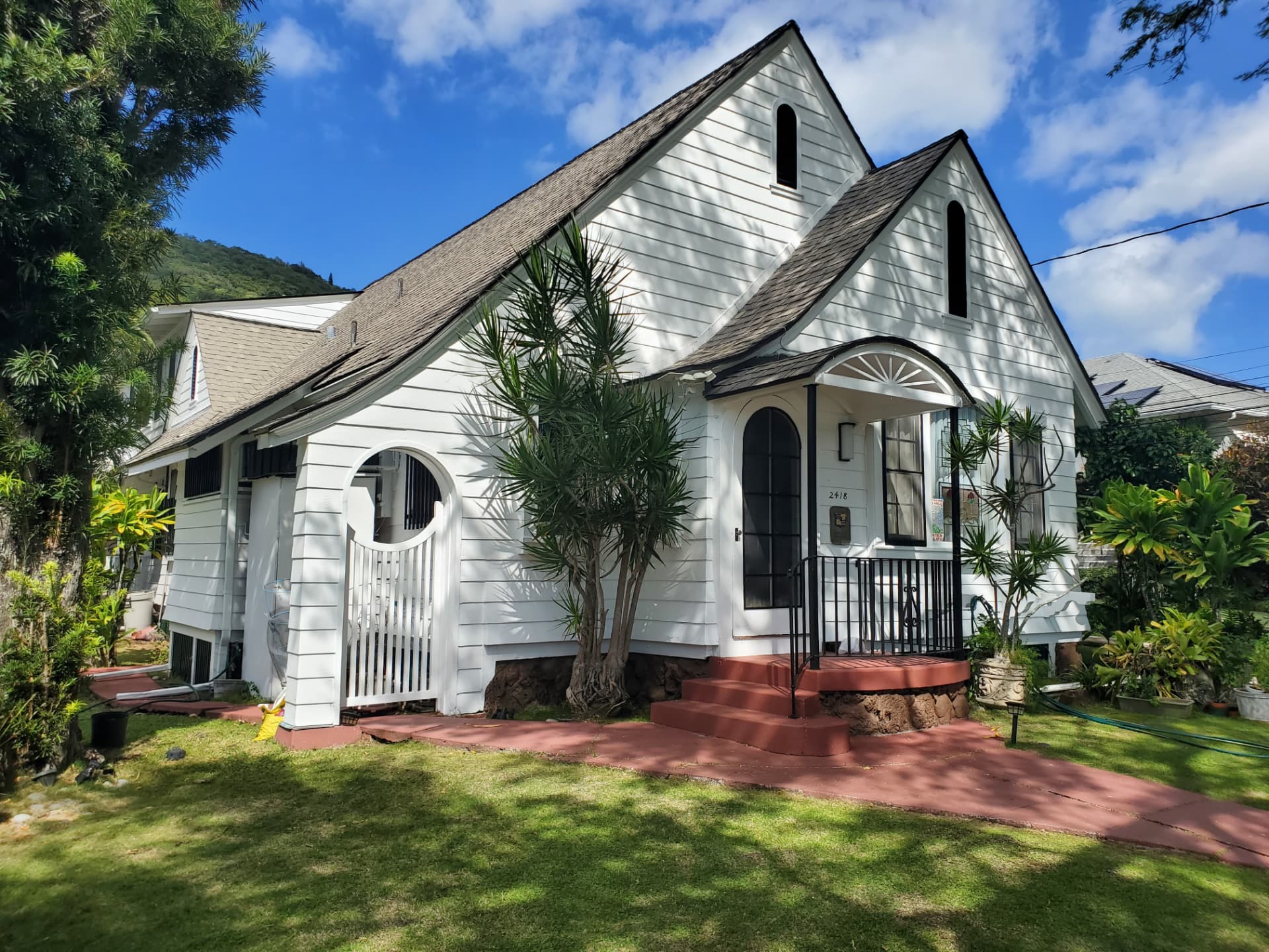 Freshly painted white plantation cottage with black trim and arched entry in Honolulu