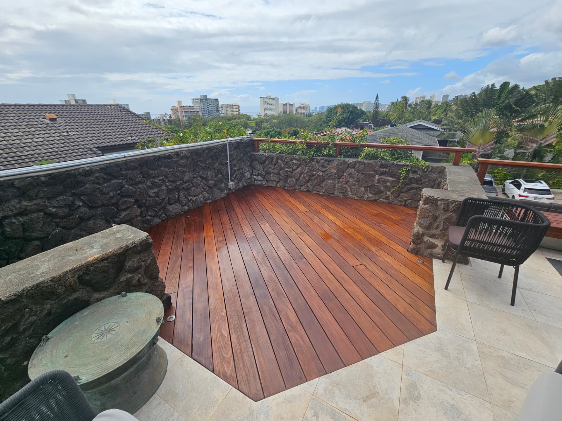 Freshly stained hardwood deck with lava rock wall and Honolulu skyline behind
