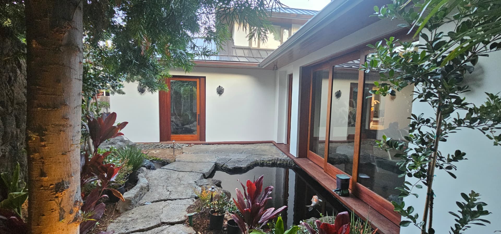 Bright white courtyard walls beside a koi pond and mahogany doors