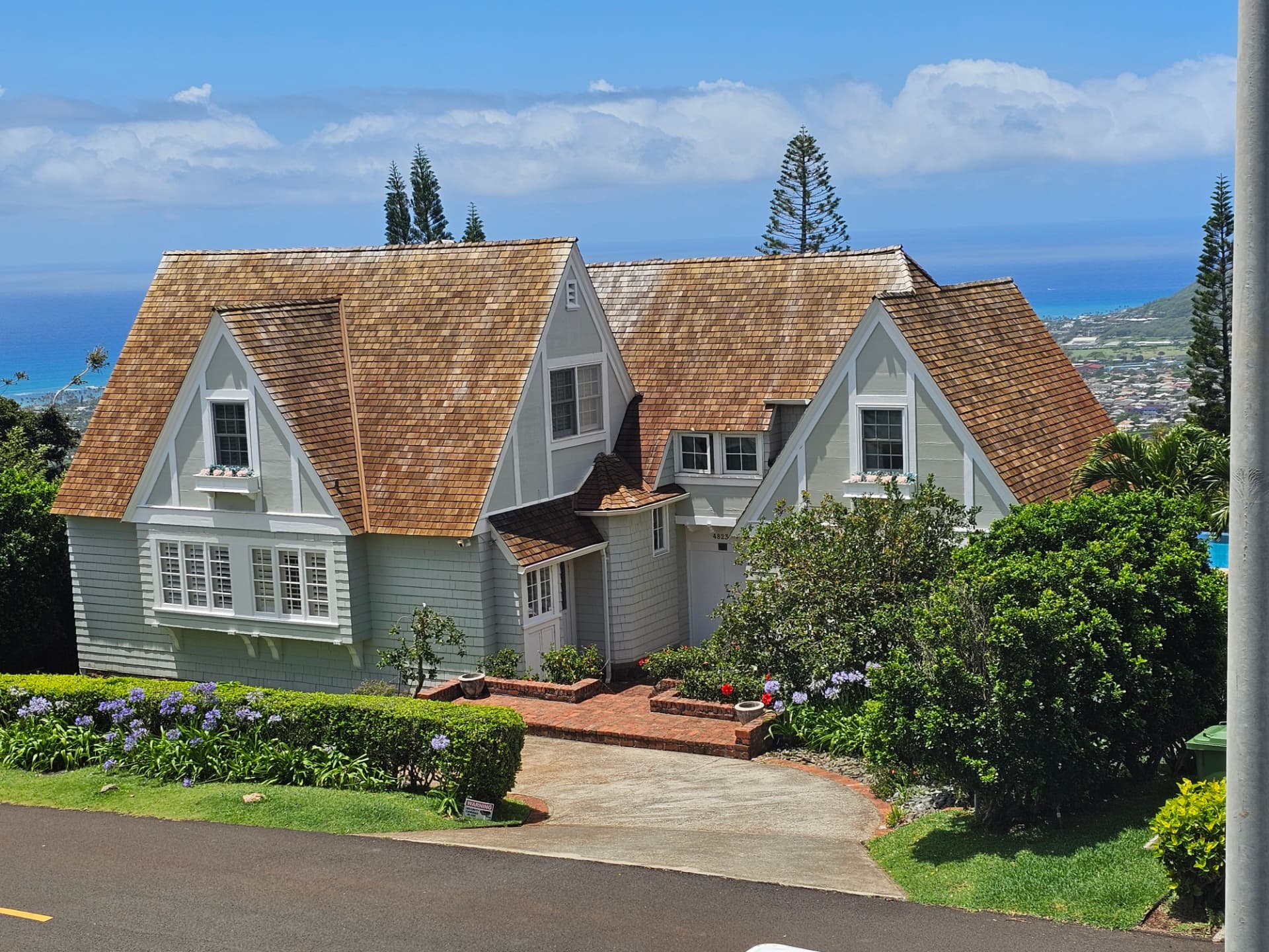 Sage green shingled home with white trim overlooking the ocean