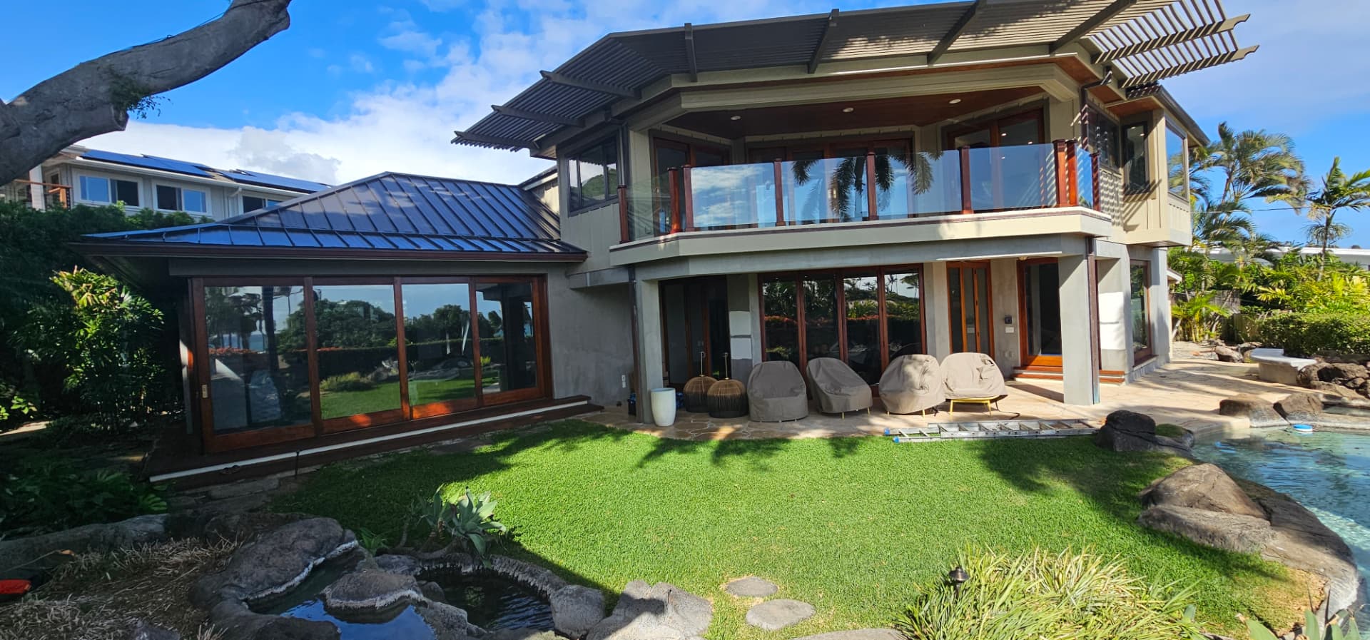 Modern Oahu estate exterior painted in warm neutrals beside a pool and lawn