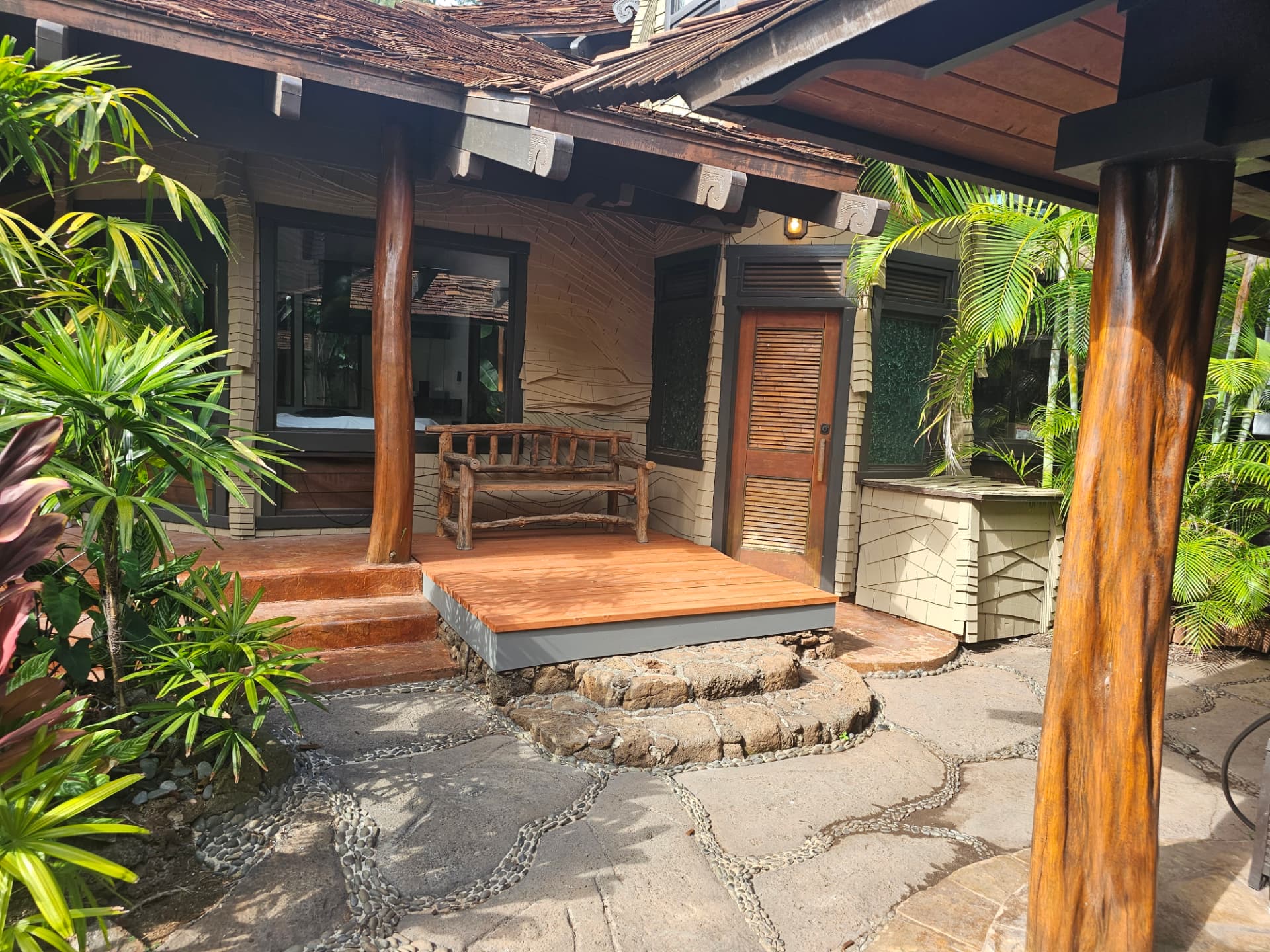Tropical bungalow entry with painted stucco walls, stained timber posts and lanai deck
