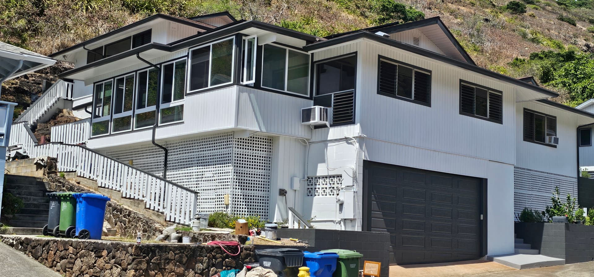 Hillside home painted white with charcoal trim, railings and garage door